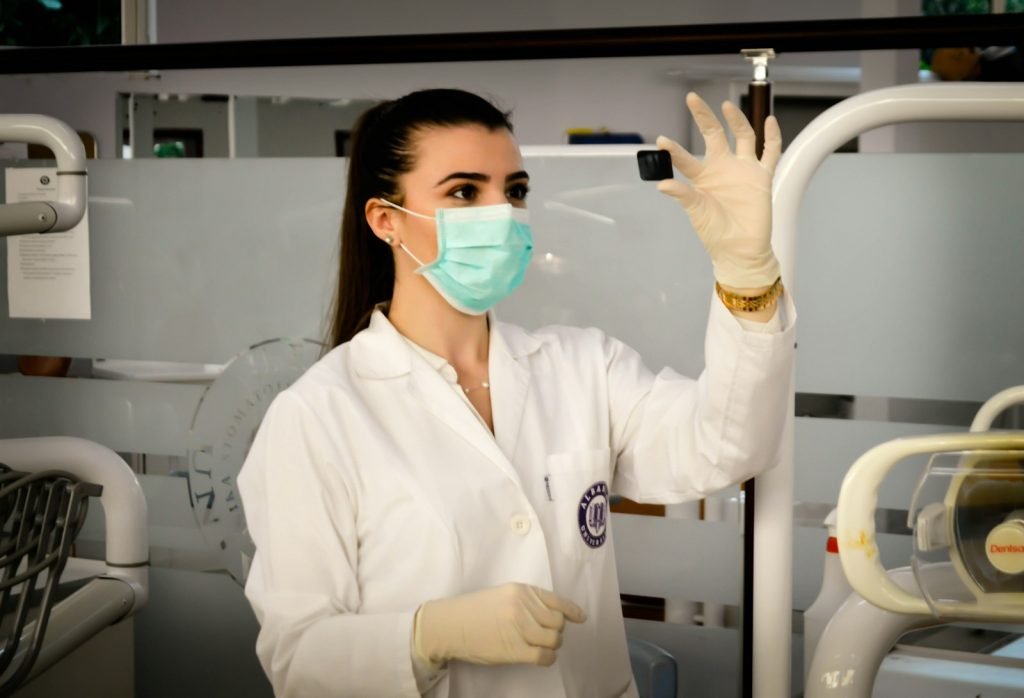 a woman wearing a mask and gloves holding a small object